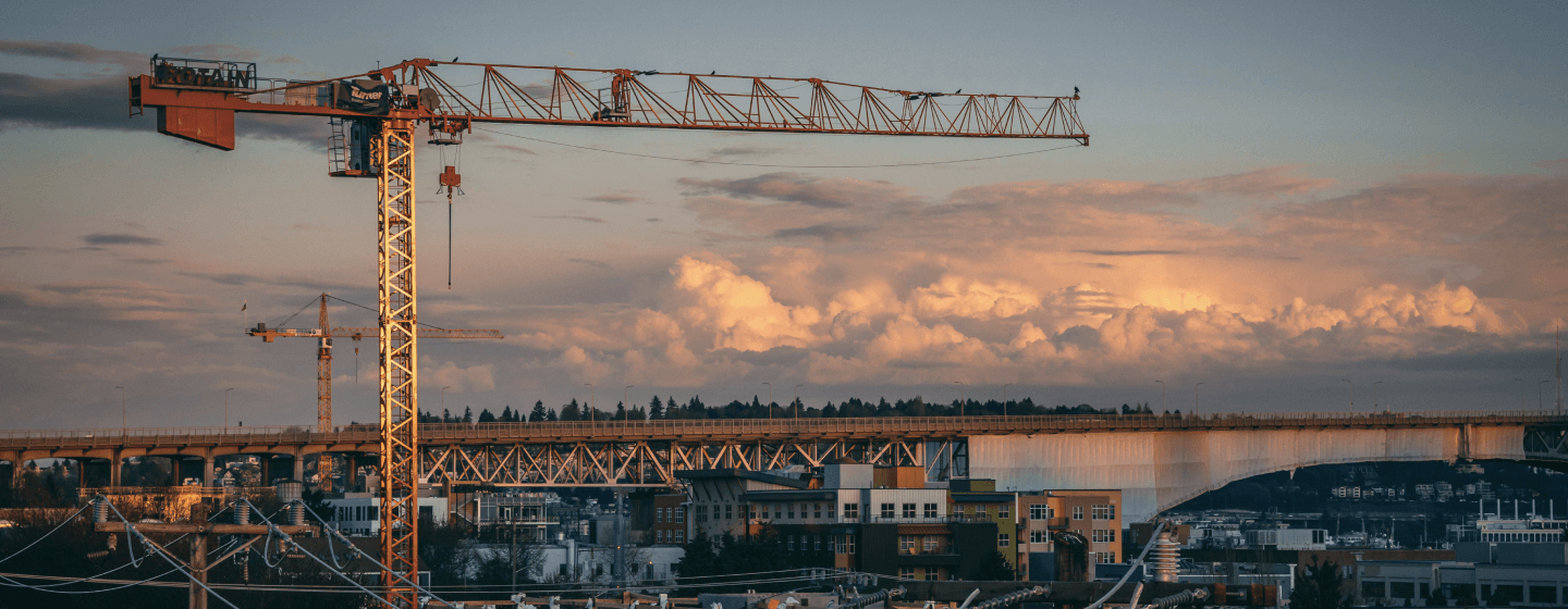 Construction cranes over a city at sunset